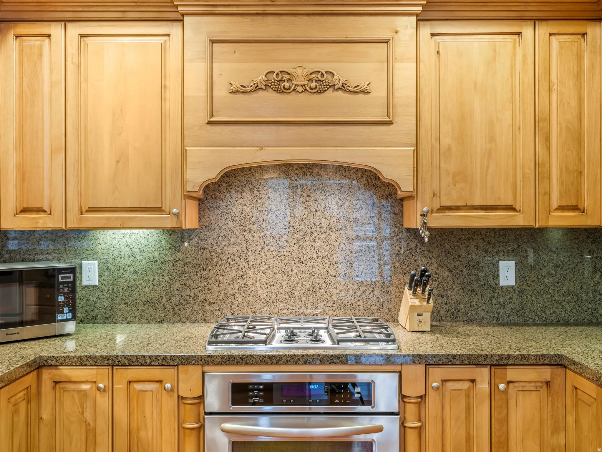 Kitchen with stainless steel appliances, extractor fan, tasteful backsplash, and ample cabinet and pantry space.