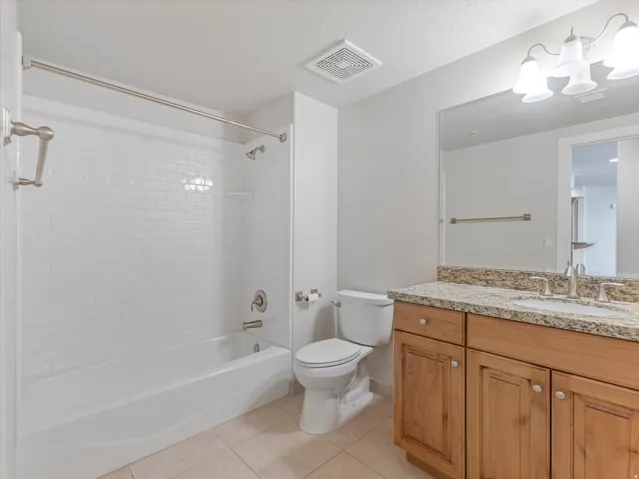 Bathroom featuring vanity, light tile patterned flooring, shower / washtub combination, hanging lights, and a textured ceiling