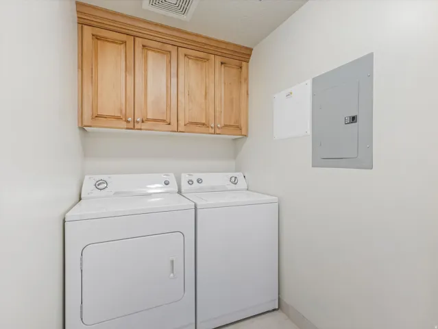 Laundry area featuring independent washer and dryer, electric panel, and cabinet space