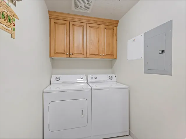 Laundry room featuring electric panel, cabinet space, and independent washer and dryer/