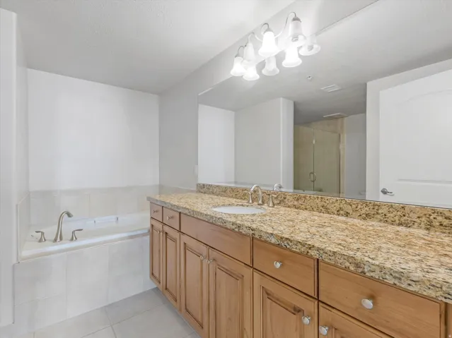 Bathroom featuring a bath, a shower stall, vanity, light tile patterned floors, and a textured ceiling