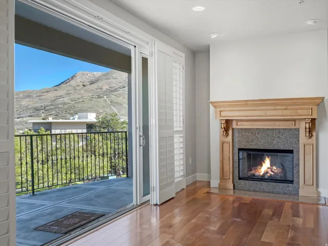 Unfurnished living room with a mountain view, wood finished floors, a glass covered fireplace, and recessed lighting