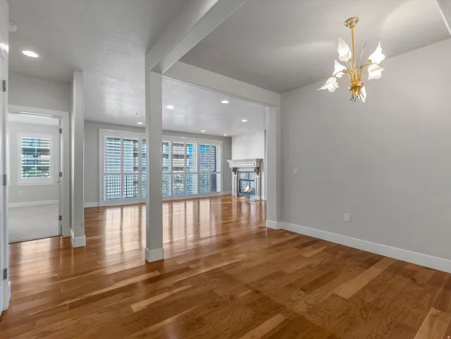 Unfurnished living room featuring a glass covered fireplace, wood finished floors, and hanging lights