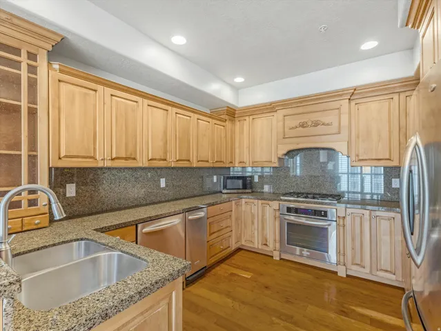 Kitchen with light wood finished floors, stainless steel appliances, decorative backsplash, light wood finish cabinetry, and recessed lighting