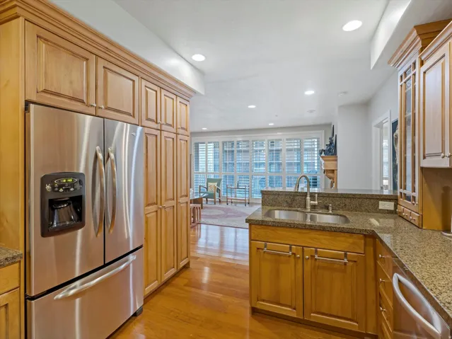 Kitchen with stainless steel appliances, a peninsula, dark stone countertops, recessed lighting, and light wood-type flooring