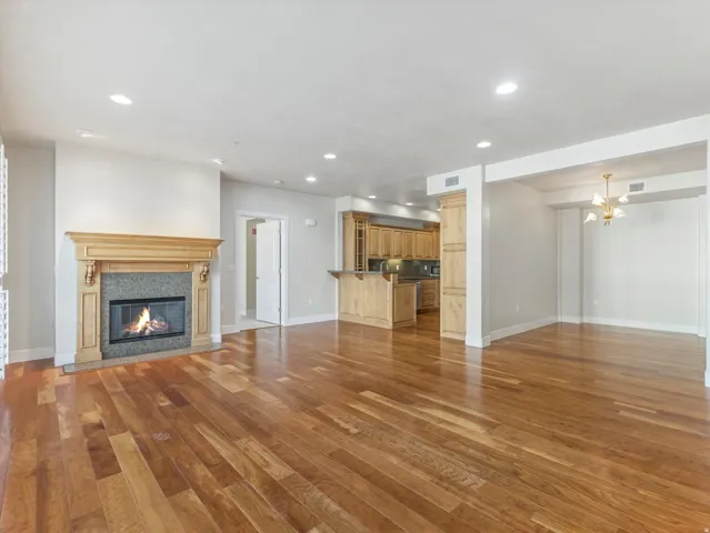 Unfurnished living room featuring light wood-style flooring, a high end fireplace, and suspended lighting
