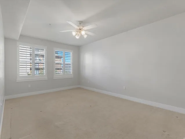 Empty room with a ceiling fan and light carpet