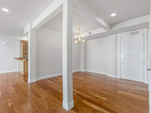 Unfurnished living room with light wood-style floors and hanging lights