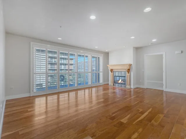 Unfurnished living room featuring wood finished floors, a tiled fireplace, and recessed lighting