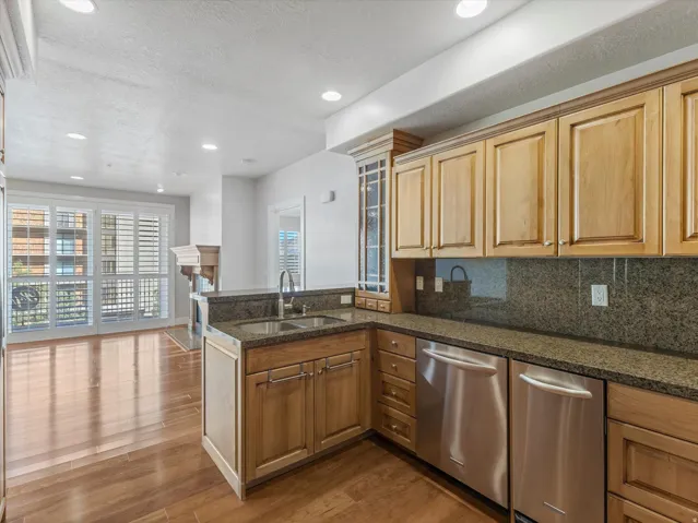 Kitchen with a peninsula, a textured ceiling, decorative backsplash, glass fronted cabinets, and dark wood finished floors
