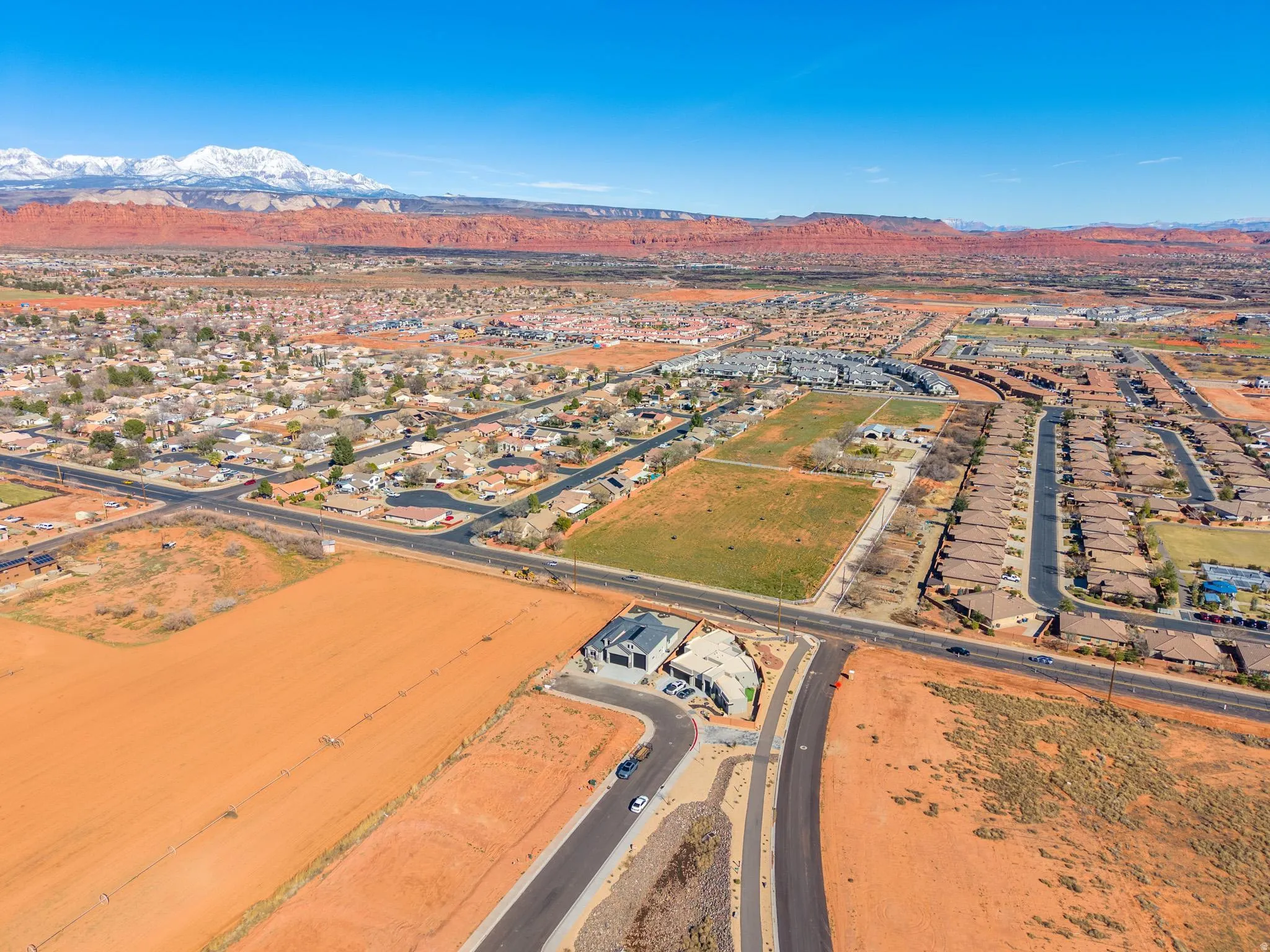 Aerial view of property and surrounding area featuring a mountainous background and nearby suburban area