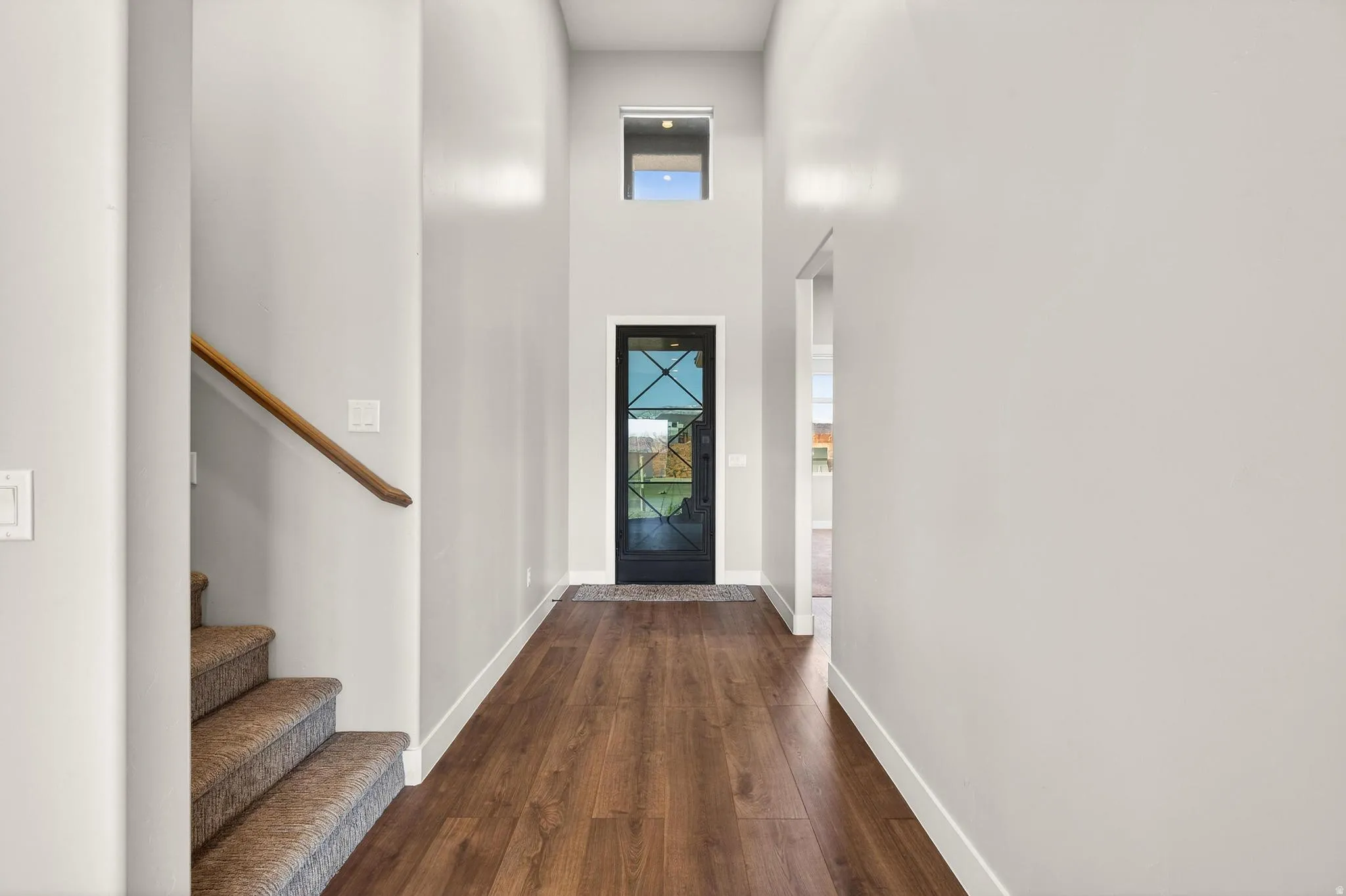 Foyer with a high ceiling, dark wood-type flooring, and healthy amount of natural light