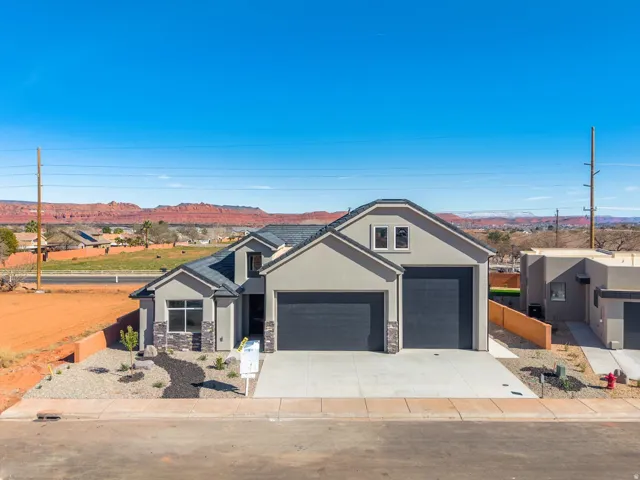 View of front facade with stucco siding, driveway, stone siding, and a mountain view