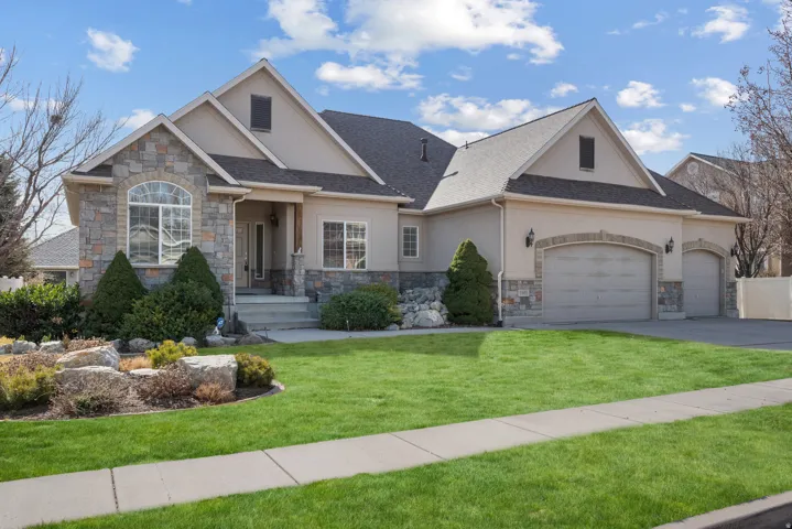 Craftsman house with stucco siding, a garage, a front yard, and stone siding