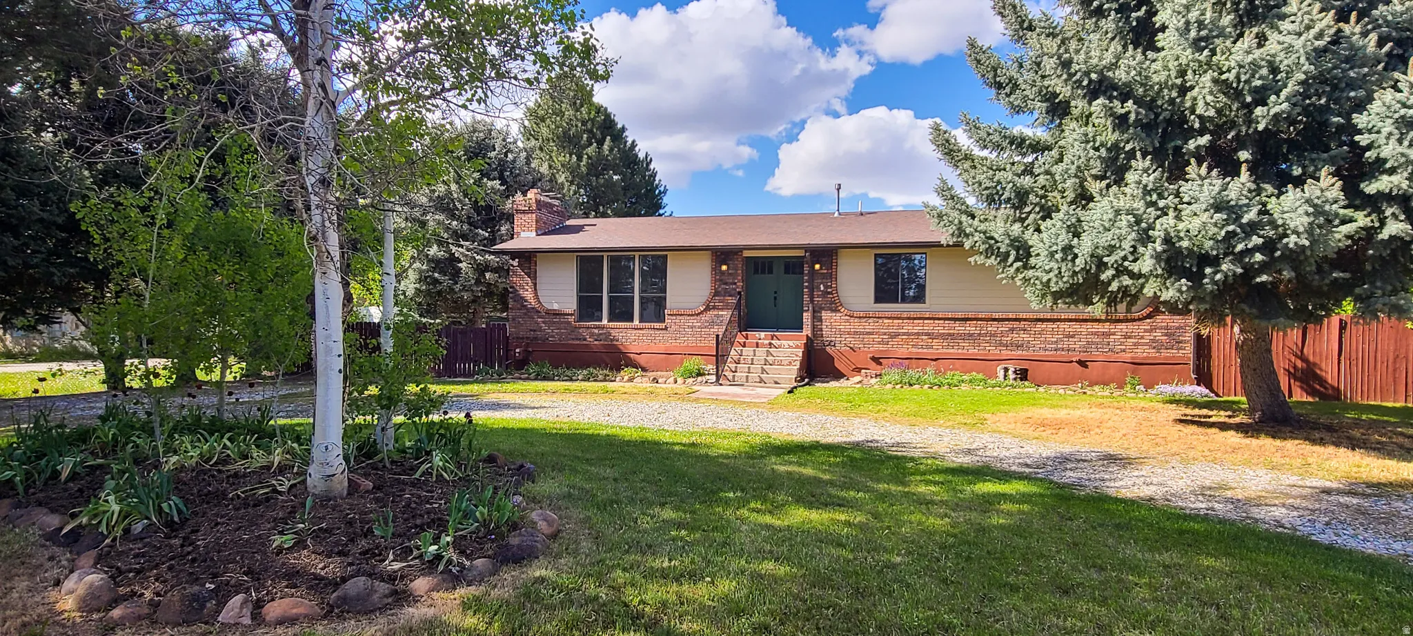 Brick and siding exterior featuring a green entry door