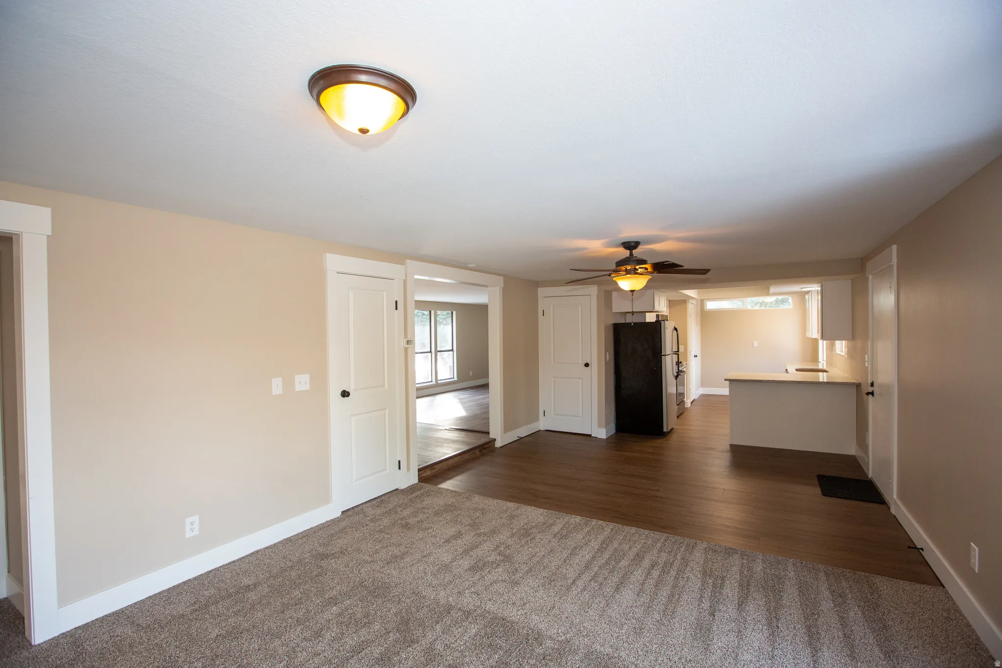 Unfurnished family room with a ceiling fan and dark LVP floors