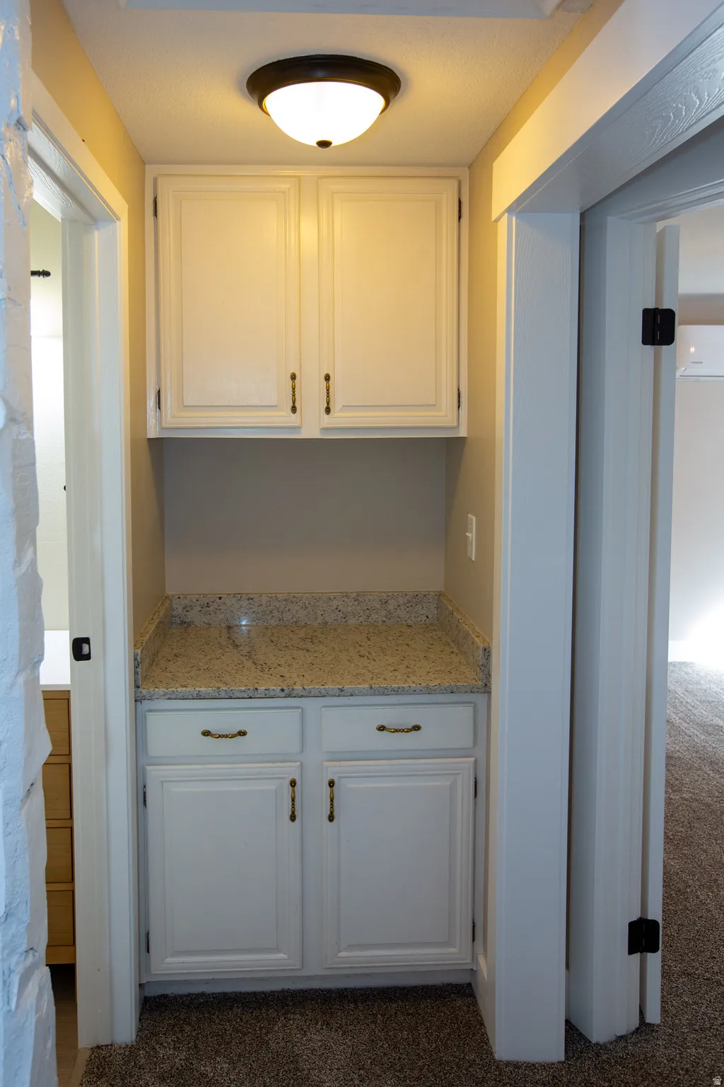 Hall cabinet and aounter featuring granite countertops, white cabinetry, and dark colored carpet