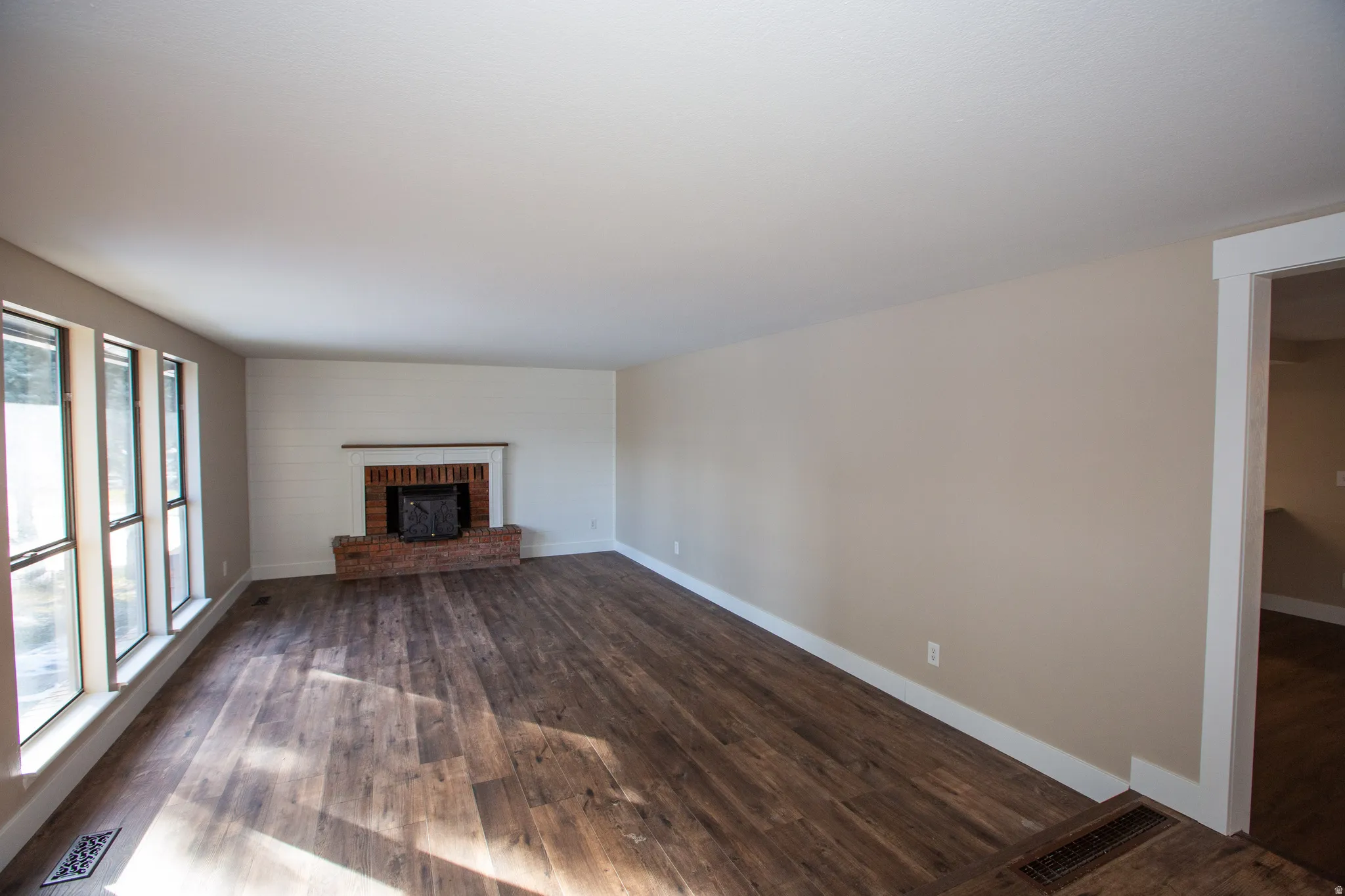 Lliving room with dark LVP floors and a brick fireplace