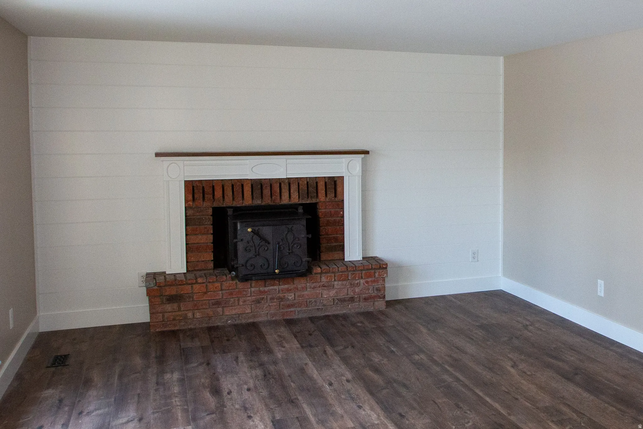 Unfurnished living room with darkLVP floors and a fireplace