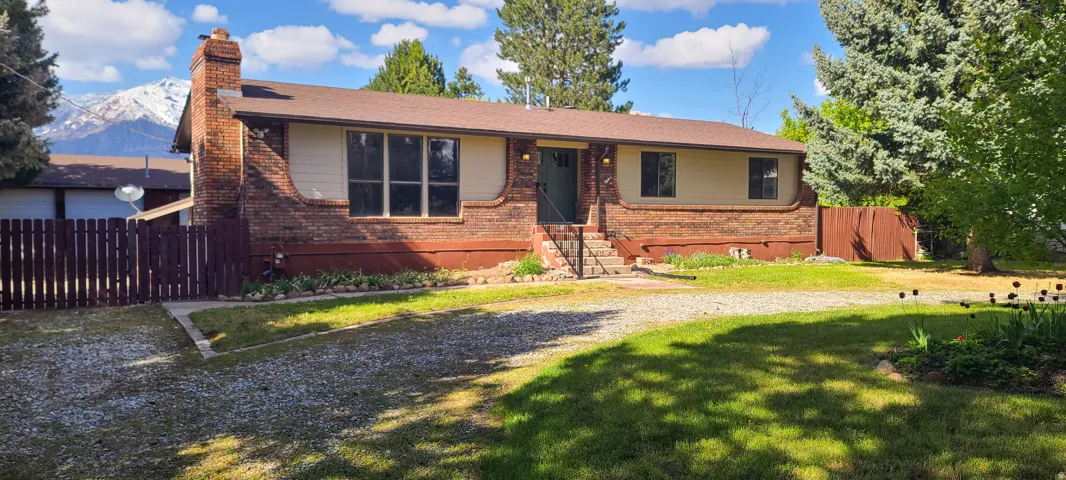 Brick and siding exterior with a brown roof and a rock driveway