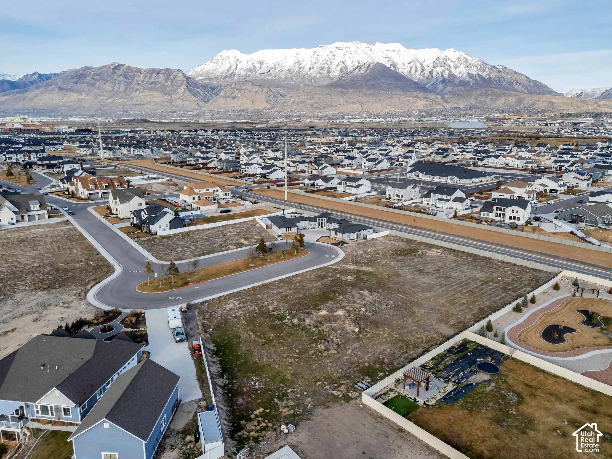 Aerial view of property and surrounding area featuring nearby suburban area and a mountain backdrop