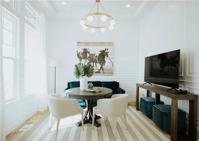 Dining space with a decorative wall, light wood-style flooring, suspended lighting, and a tray ceiling