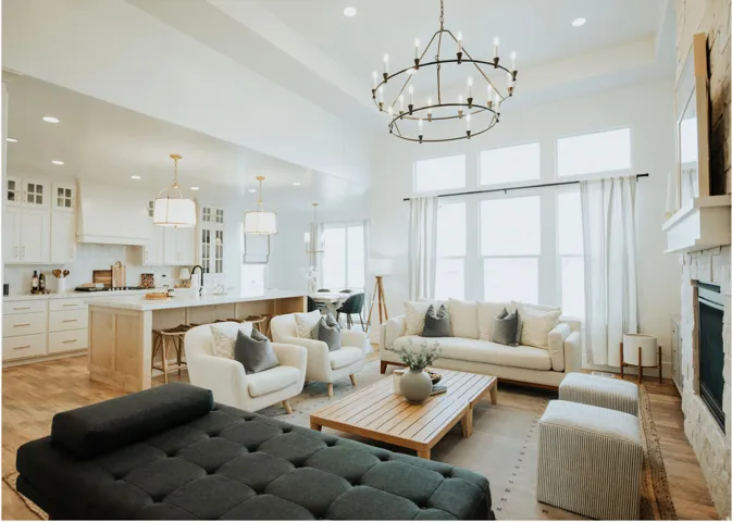 Living area with light wood-style flooring, a glass covered fireplace, hanging lights, and a high tray ceiling