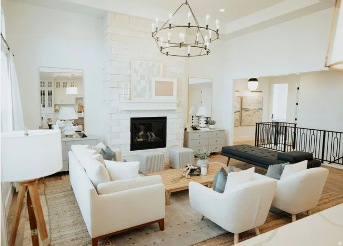 Living room featuring wood finished floors, a stone fireplace, a chandelier, and a high ceiling