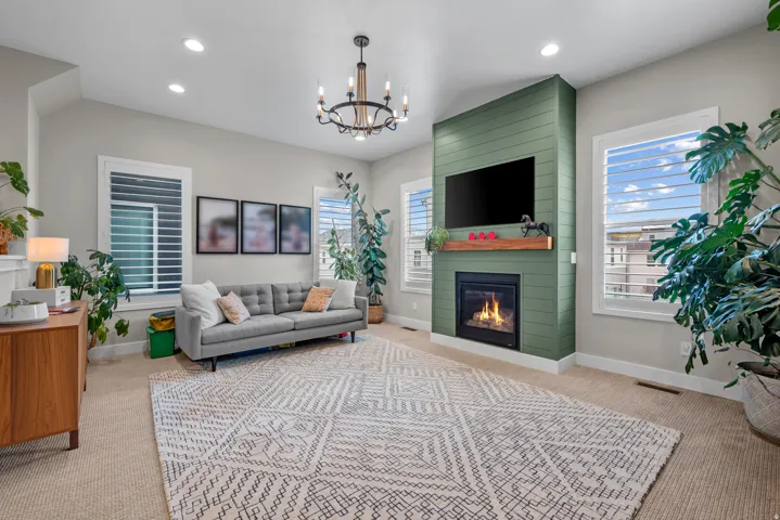 Living area featuring light carpet, a large fireplace, hanging lights, and healthy amount of natural light