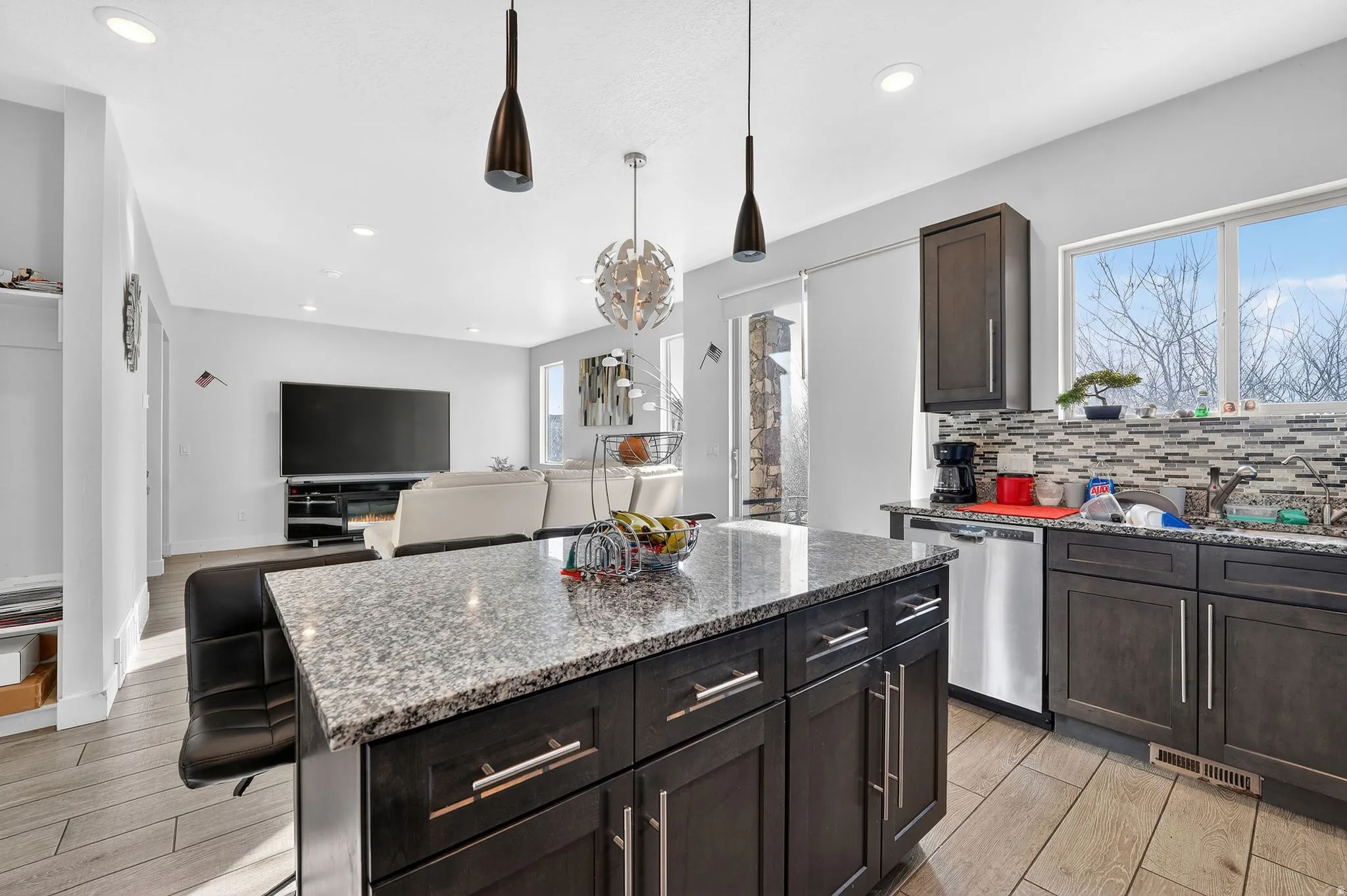 Kitchen with dark stone counters, tasteful backsplash, wood tiled floors, and stainless steel dishwasher