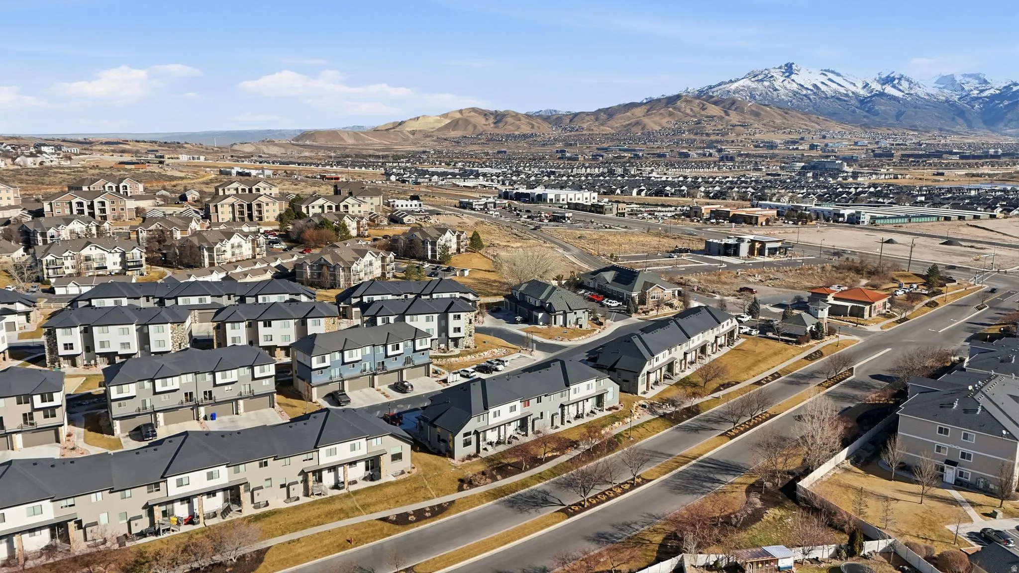 Aerial view of property and surrounding area featuring mountains and nearby suburban area