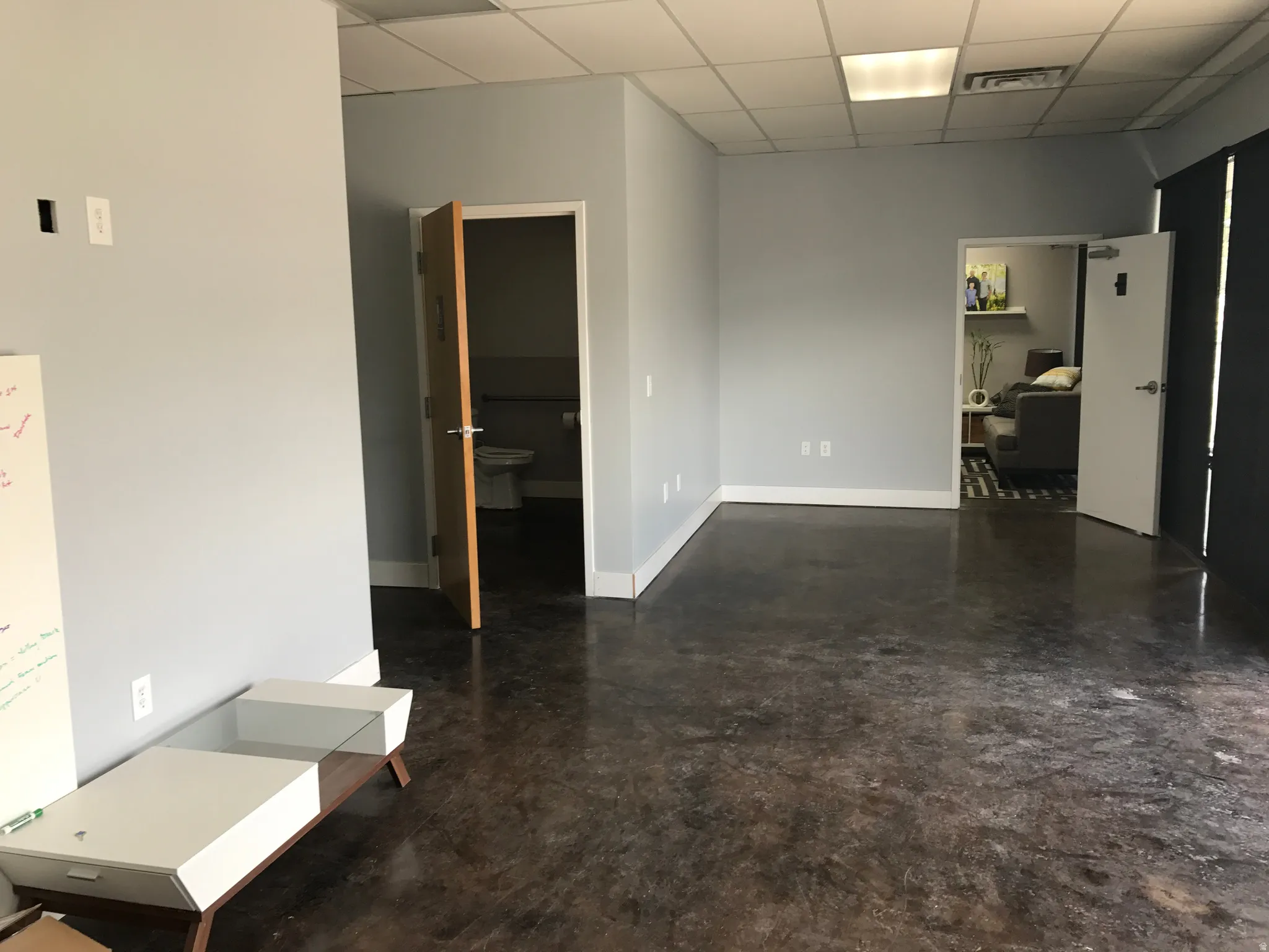 Unfurnished room with a drop ceiling and finished concrete flooring