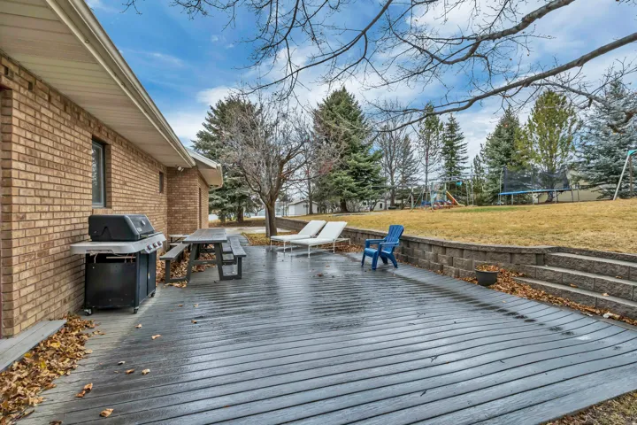 Wooden deck with a trampoline, a playground, grilling area, and a lawn