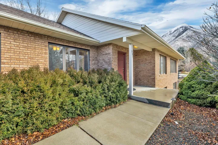 View of exterior entry with covered porch, brick siding, and a mountain view