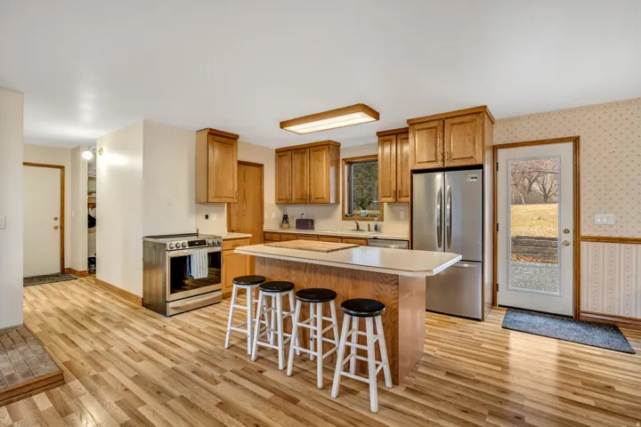 Kitchen featuring light countertops, stainless steel appliances, wallpapered walls, a kitchen breakfast bar, and a center island