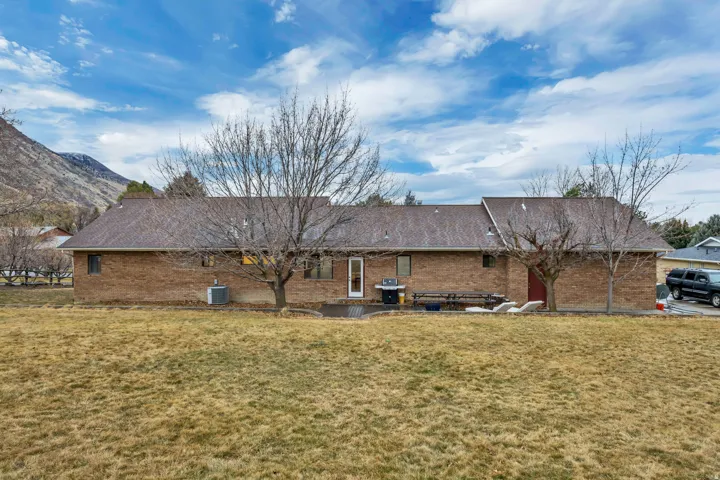 Rear view of property with a patio area, brick siding, and a yard