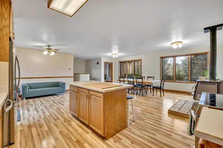 Kitchen featuring wallpapered walls, light wood finished floors, a breakfast bar, a kitchen island, and wood finish cabinets