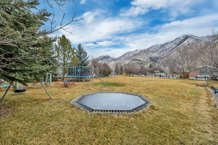 View of green lawn featuring a trampoline and a mountain view