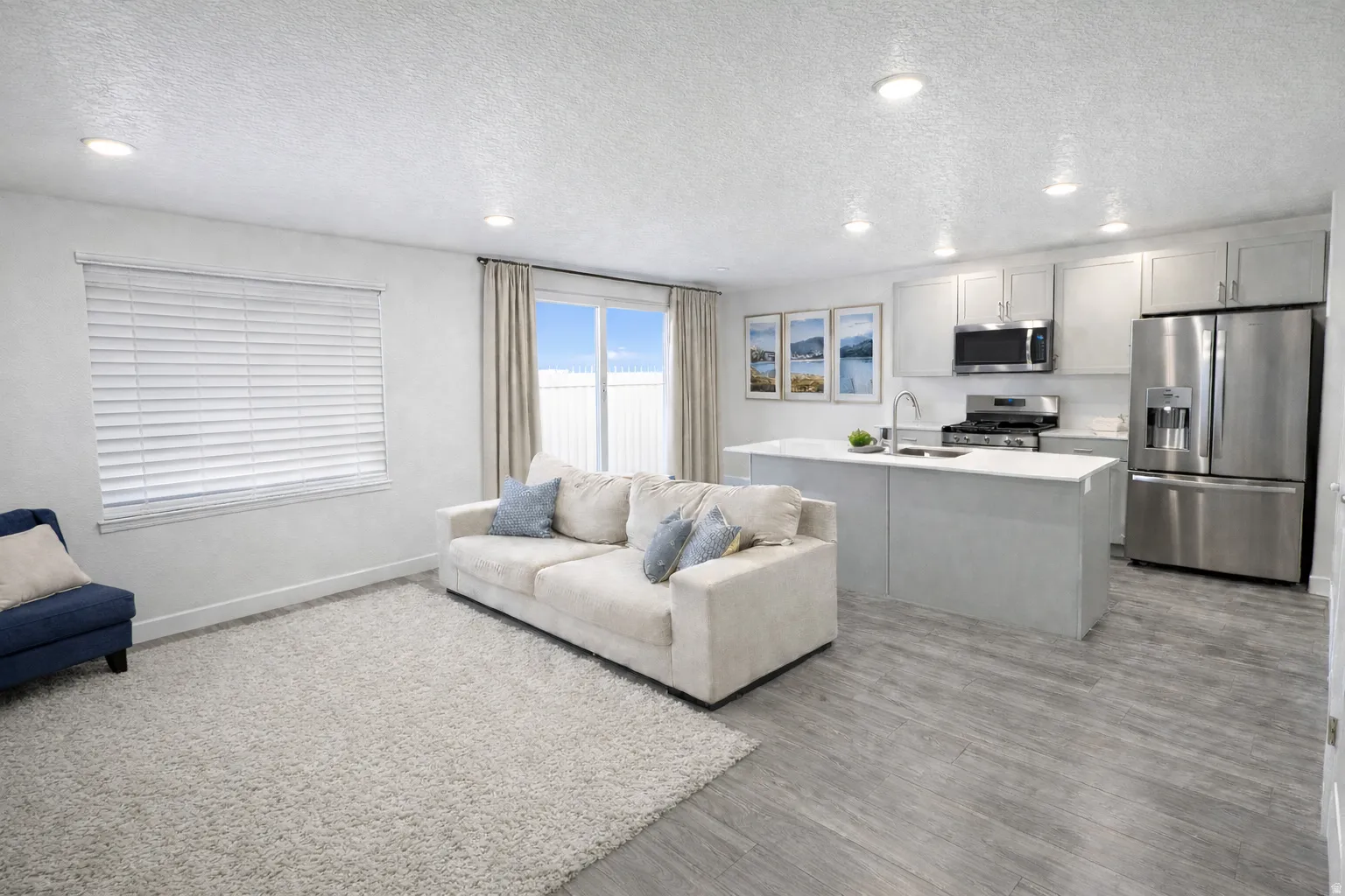 Living room with a textured ceiling, recessed lighting, and light wood-style floors
