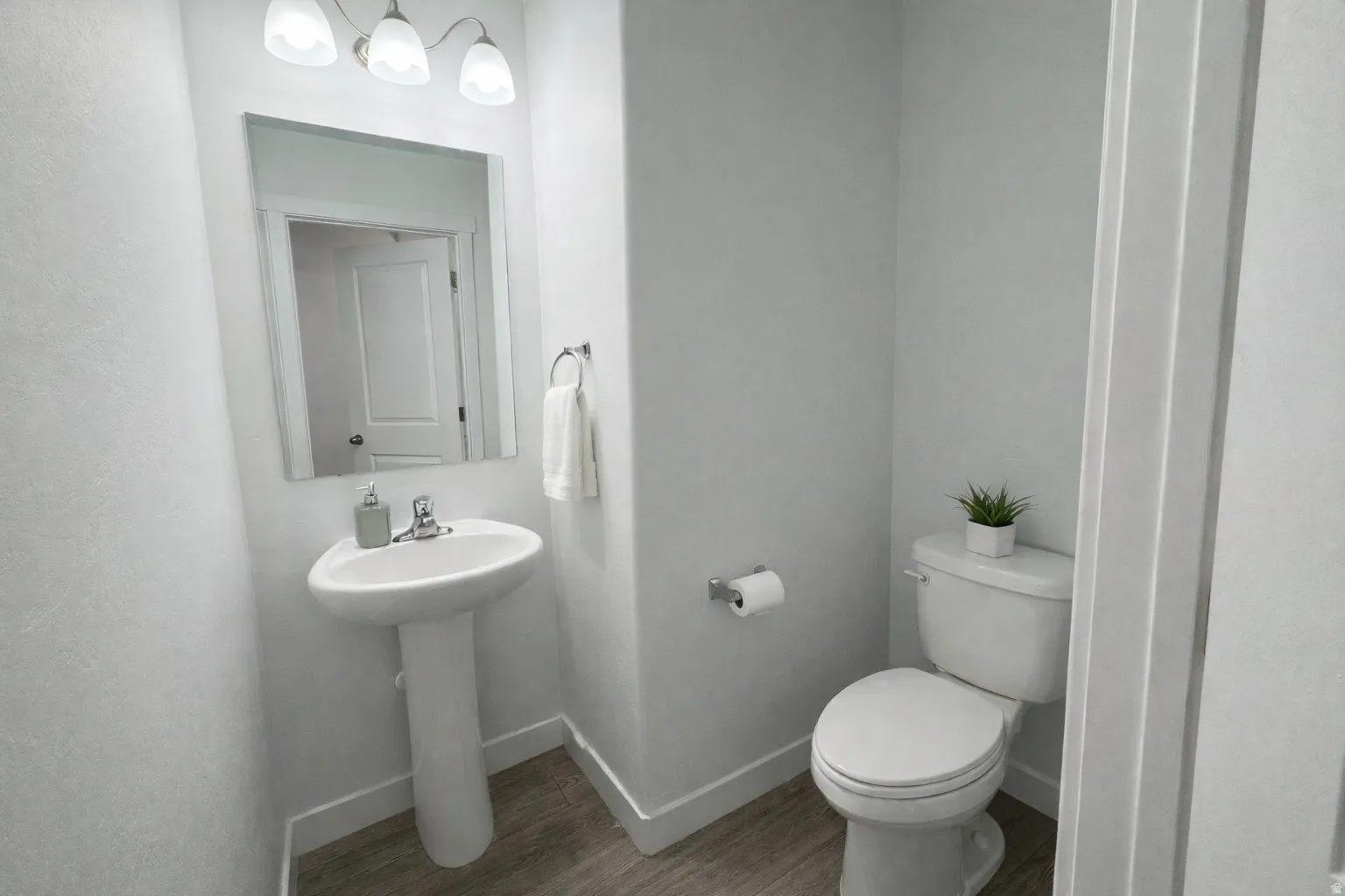 Half bathroom featuring toilet and wood finished floors