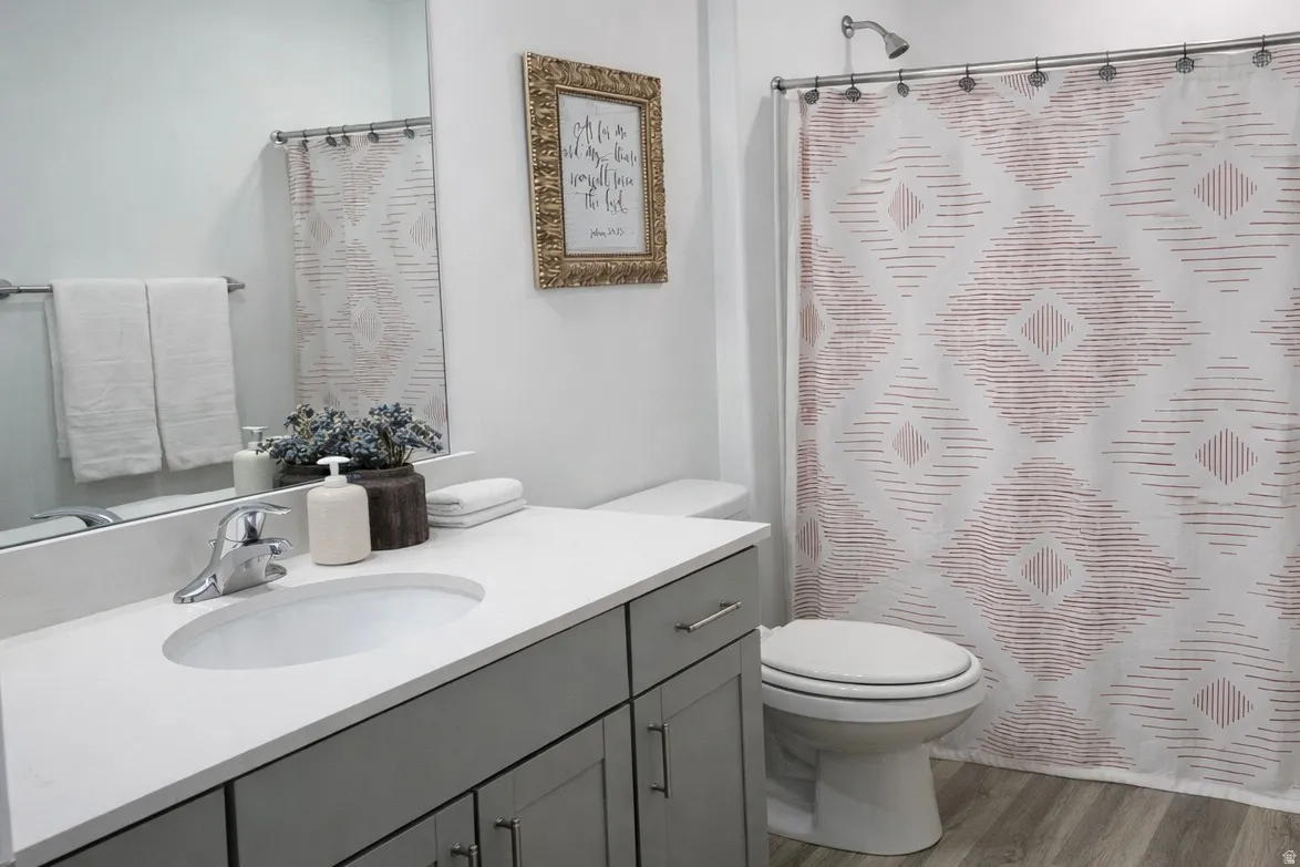 Bathroom with vanity, a shower with shower curtain, and light wood-style floors