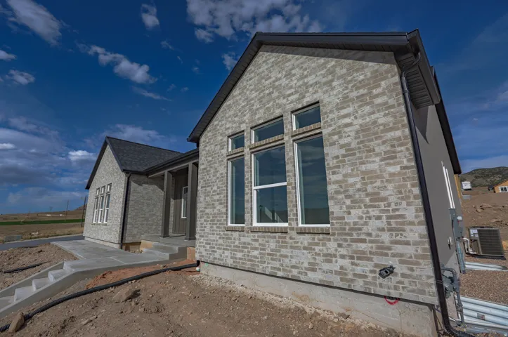 View of side of home with brick siding and a central AC unit