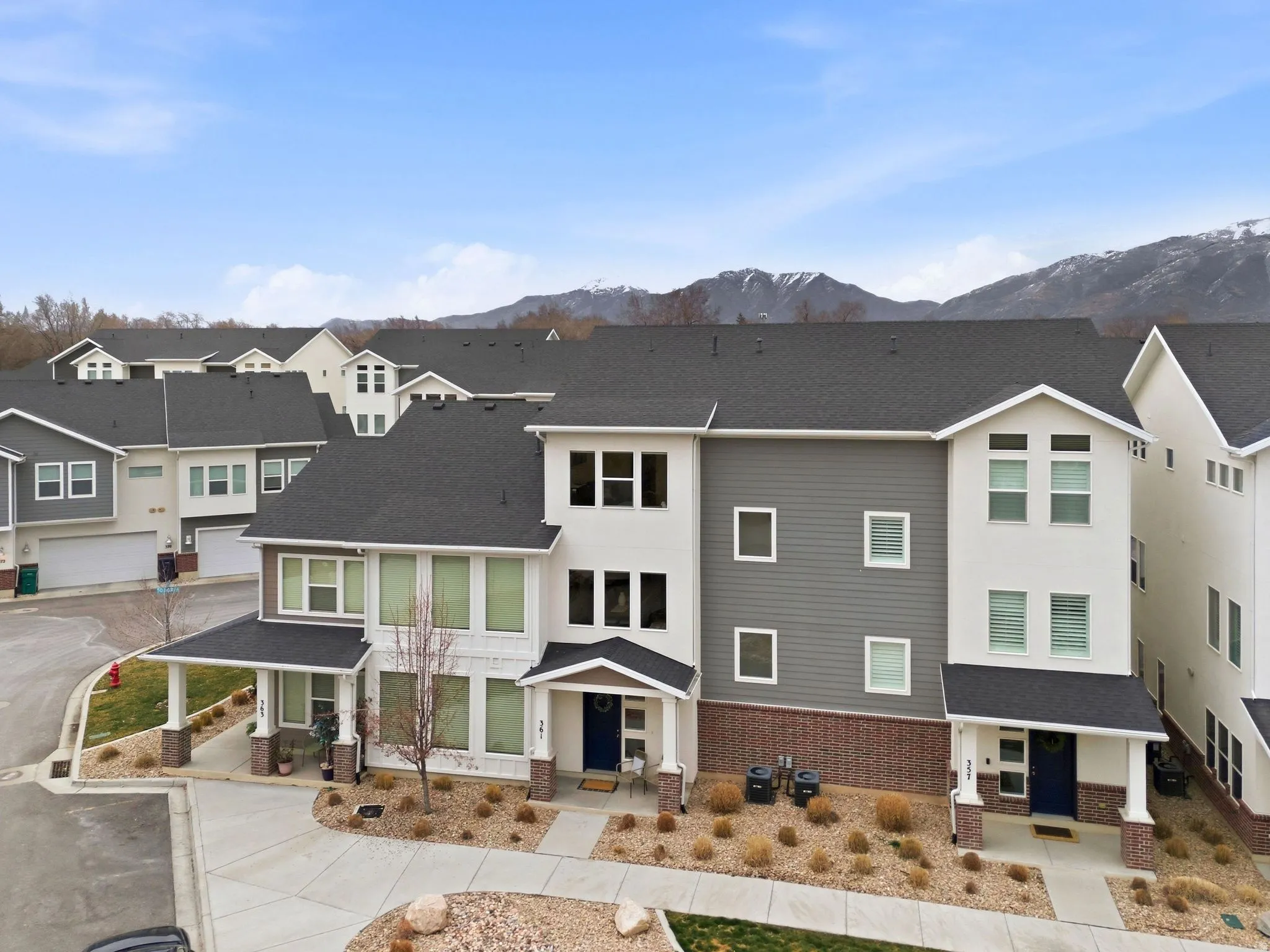 View of front facade with a residential view, a shingled roof, brick siding, covered porch, and a mountain view