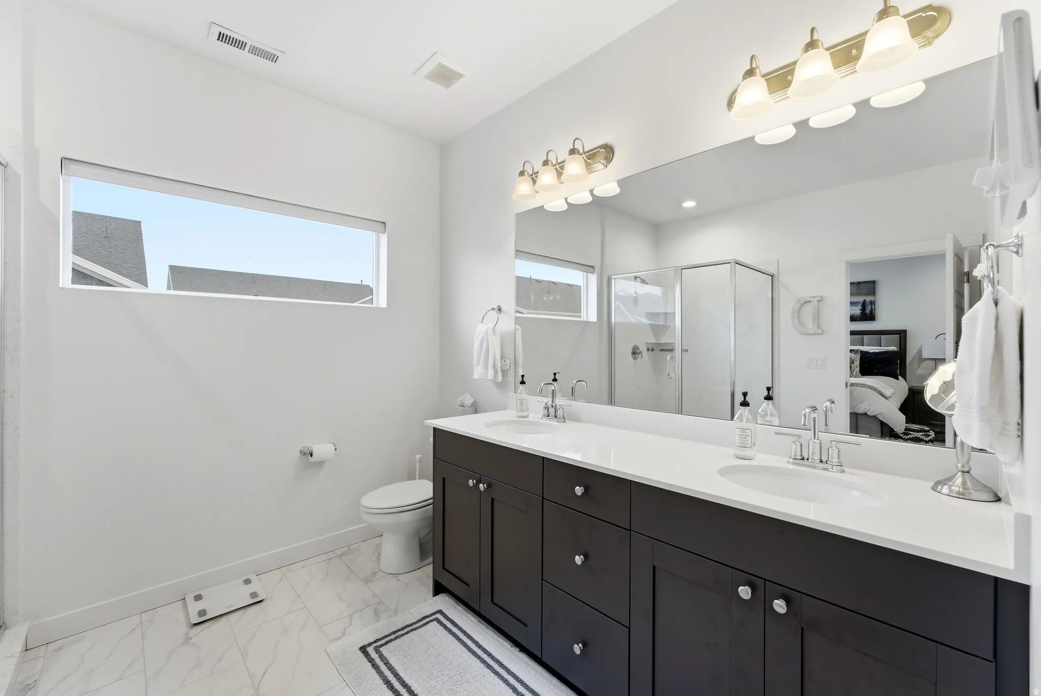 Bathroom with ensuite bathroom, double vanity, a stall shower, and light marble finish flooring