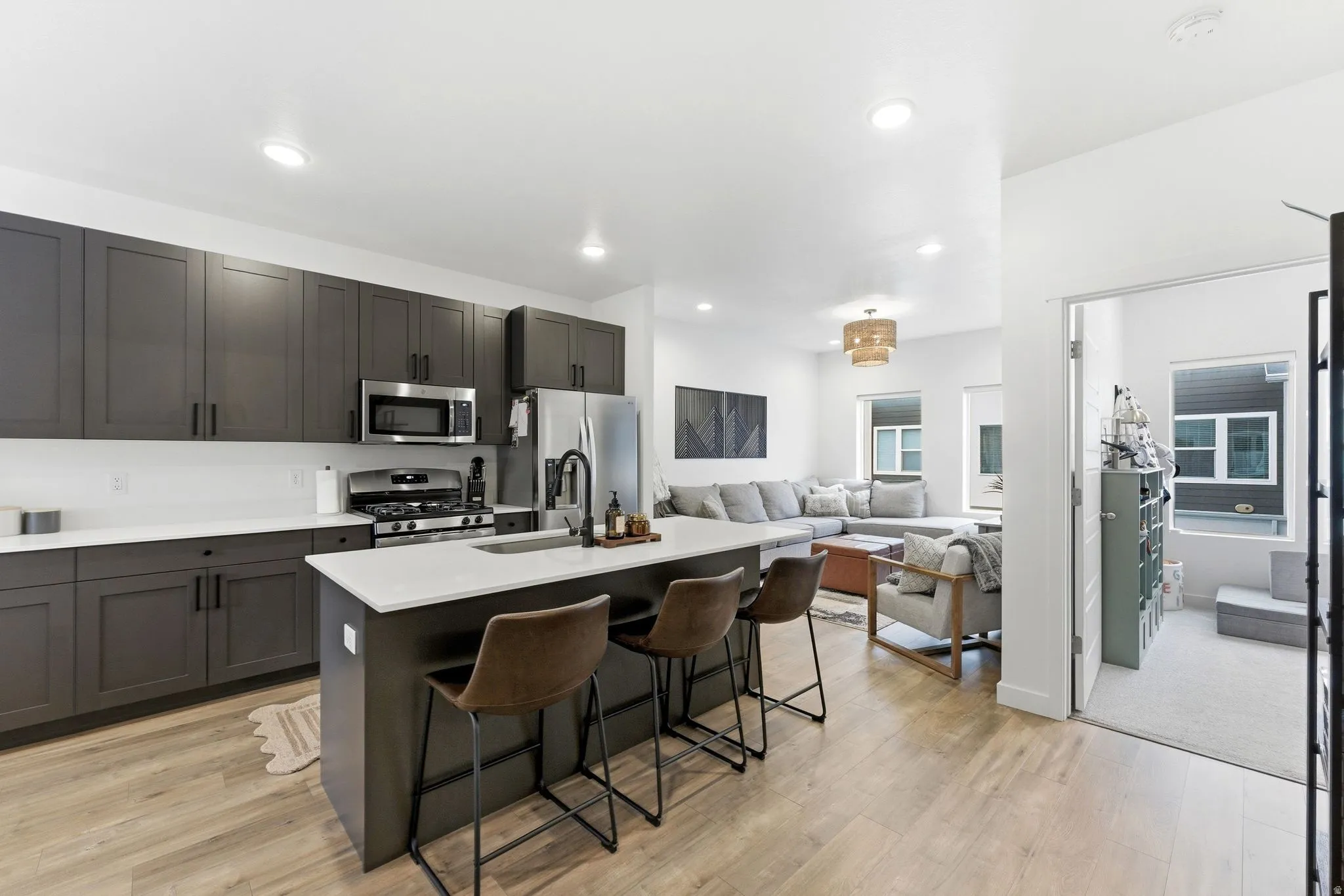 Kitchen with a kitchen island with sink, open floor plan, stainless steel appliances, light wood-style flooring, and recessed lighting