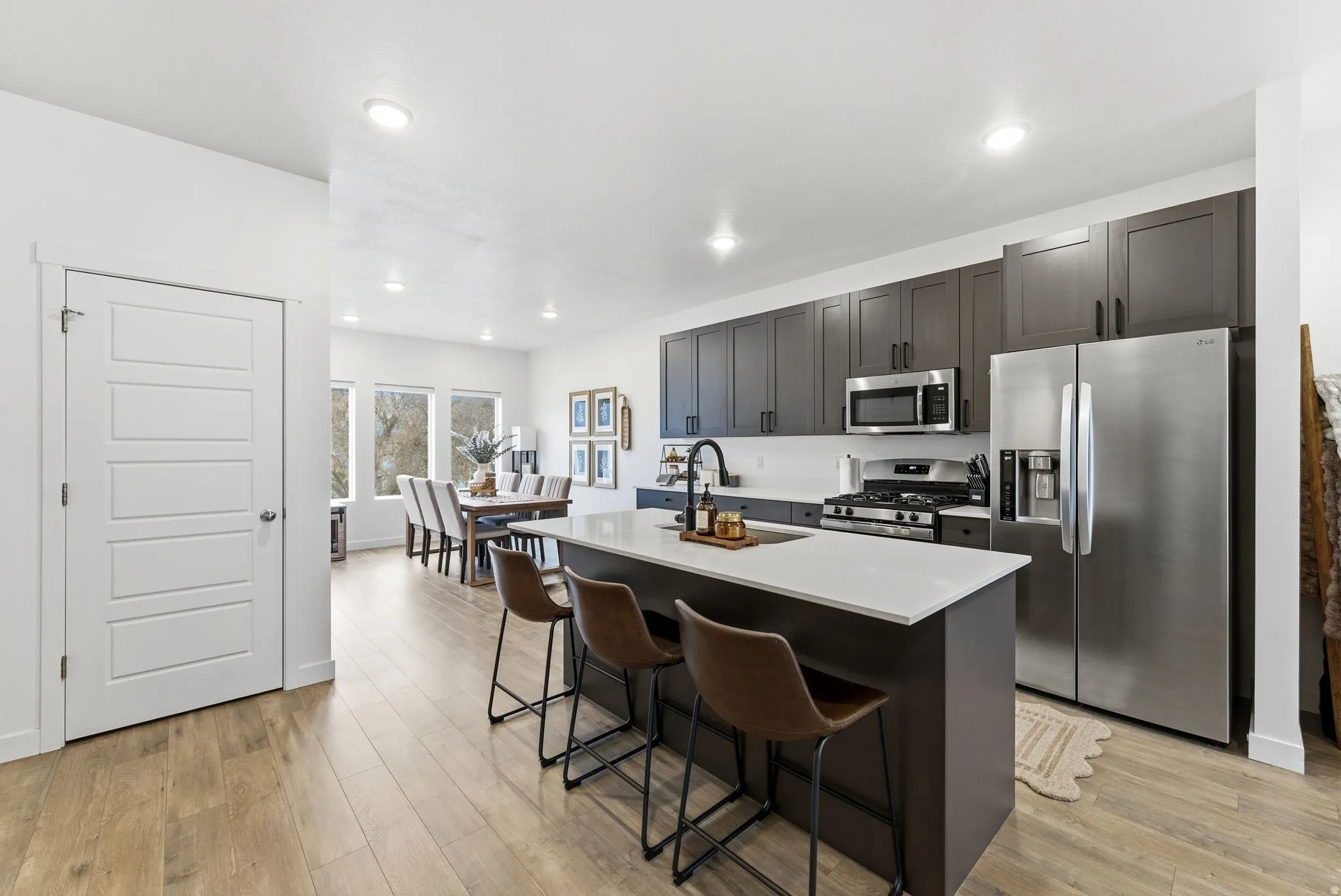 Kitchen with stainless steel appliances, a center island with sink, light wood-style flooring, a breakfast bar area, and recessed lighting