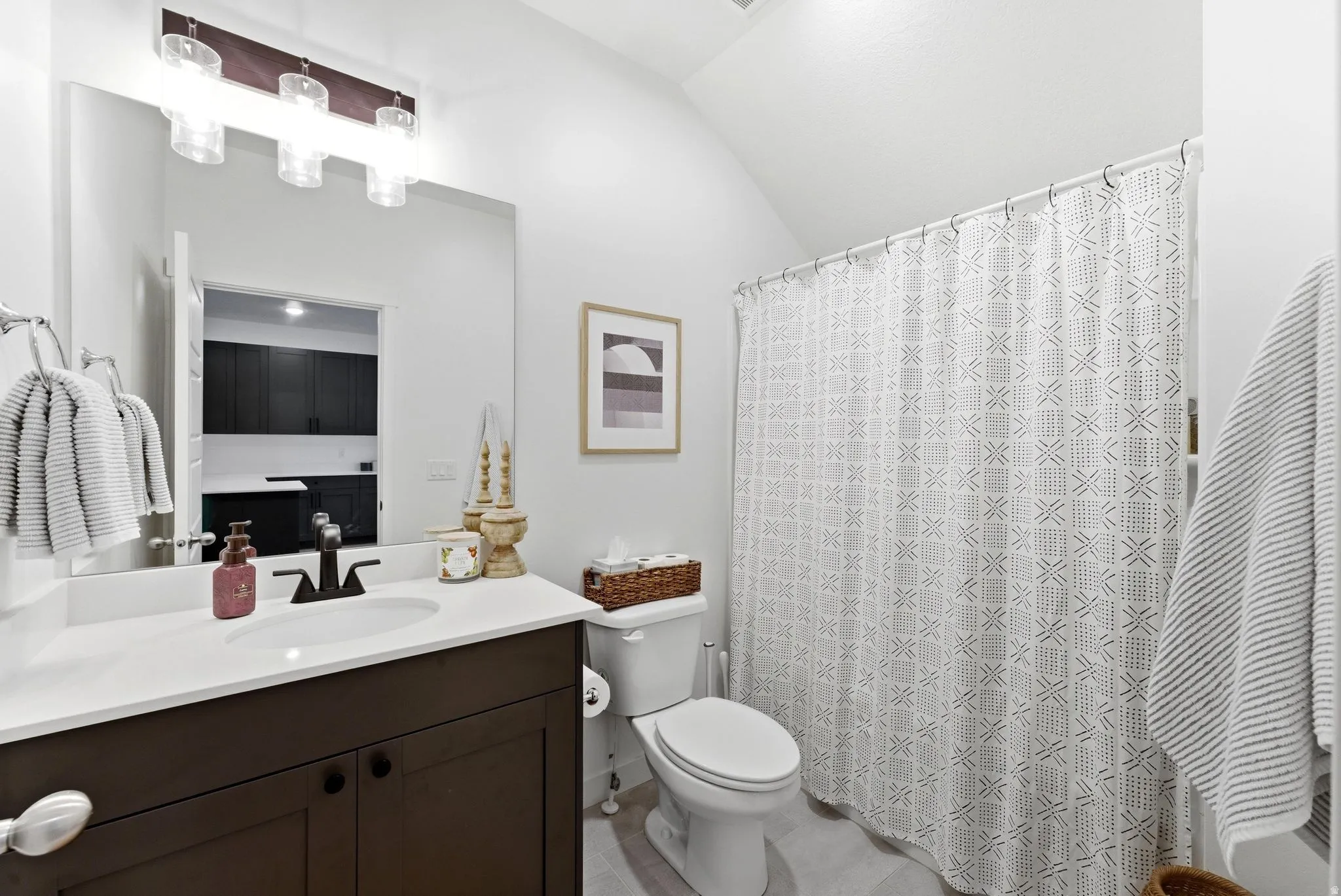 Bathroom with vanity, vaulted ceiling, curtained shower, and light tile patterned flooring