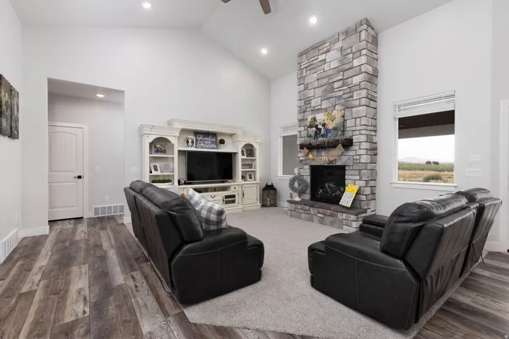 Living room with vaulted ceiling, a ceiling fan, dark wood-style floors, and a fireplace
