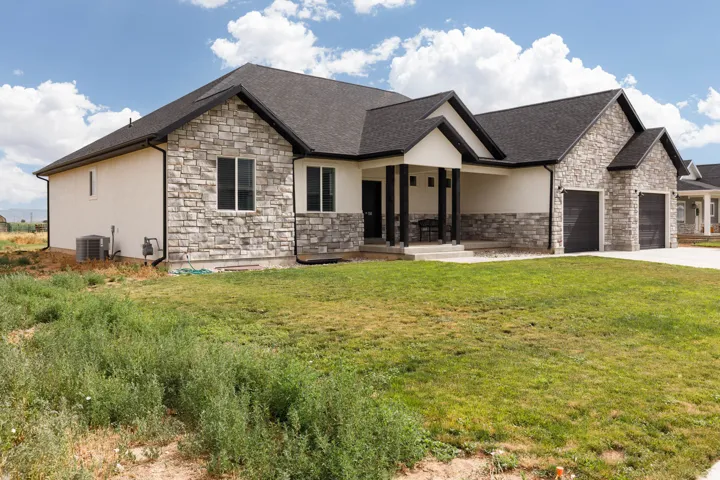 View of front of property with stone siding, a front lawn, a porch, and an attached garage
