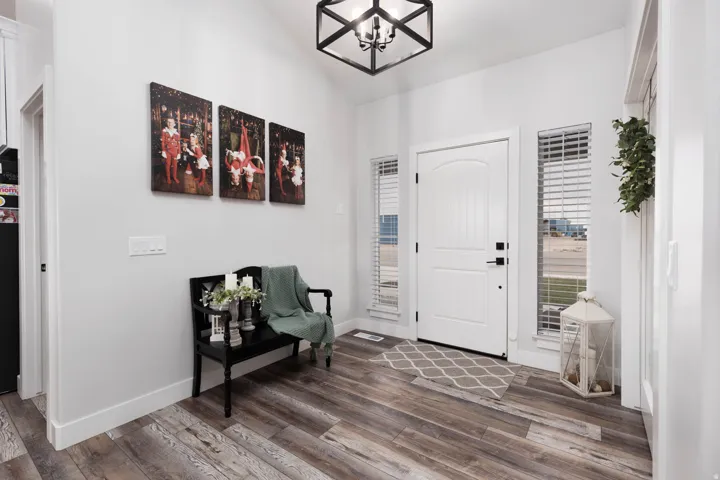 Foyer with a chandelier, dark wood-style flooring, and vaulted ceiling